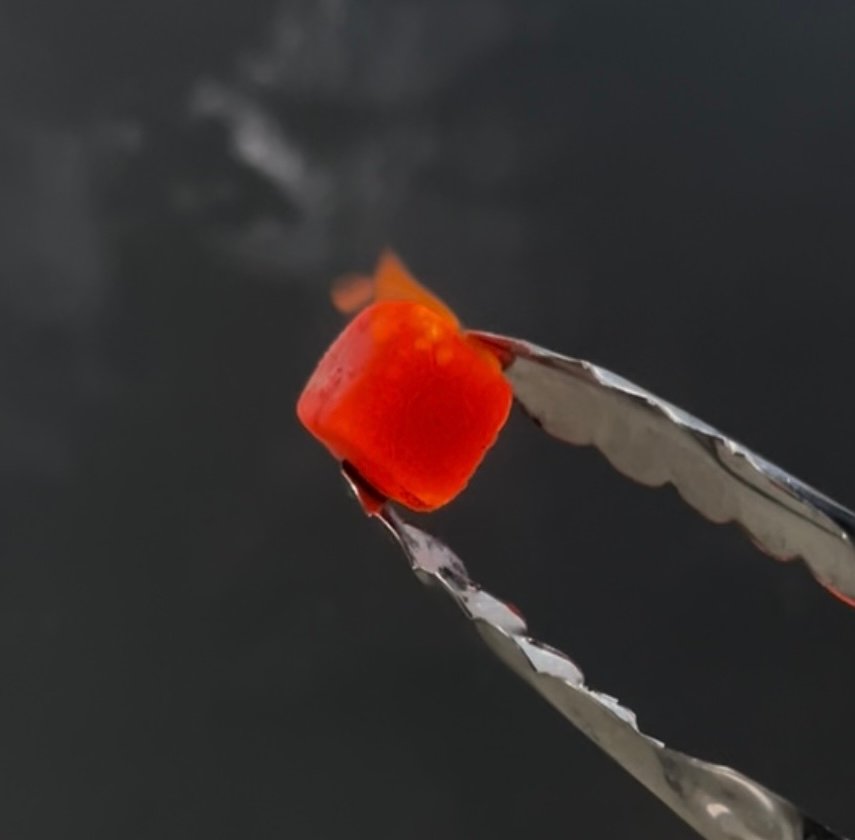 A single briquette glowing red at controlled high heat